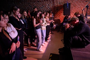 Dawid Tyszkowski "Nadal nie śpię" w Piwnicach TCK - Siedzący na skraju sceny Dawid śpiewający do tarnowskiej publiczności