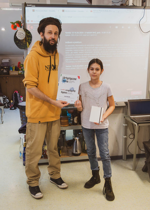 Artystyczne Ferie - tydzień II - Na fotografii uwieczniono grupę uczestników – dzieci, młodzież oraz dorosłych – zaangażowanych w warsztaty tworzenia Artbooków. Widoczne są różnorodne narzędzia, w tym prasa drukarska, z których korzystają pod czujnym okiem prowadzących.