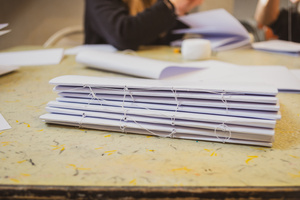 Artystyczne Ferie - tydzień II - Na fotografii uwieczniono grupę uczestników – dzieci, młodzież oraz dorosłych – zaangażowanych w warsztaty tworzenia Artbooków. Widoczne są różnorodne narzędzia, w tym prasa drukarska, z których korzystają pod czujnym okiem prowadzących.