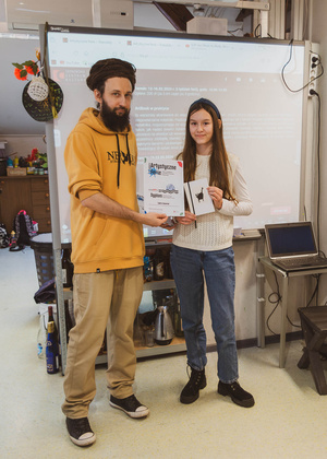 Artystyczne Ferie - tydzień II - Na fotografii uwieczniono grupę uczestników – dzieci, młodzież oraz dorosłych – zaangażowanych w warsztaty tworzenia Artbooków. Widoczne są różnorodne narzędzia, w tym prasa drukarska, z których korzystają pod czujnym okiem prowadzących.