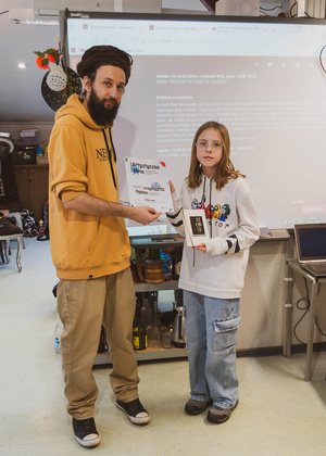 Artystyczne Ferie - tydzień II - Na fotografii uwieczniono grupę uczestników – dzieci, młodzież oraz dorosłych – zaangażowanych w warsztaty tworzenia Artbooków. Widoczne są różnorodne narzędzia, w tym prasa drukarska, z których korzystają pod czujnym okiem prowadzących.