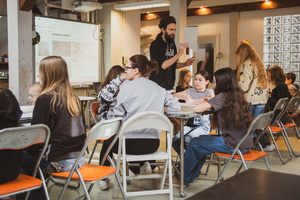 Artystyczne Ferie - tydzień II - Na fotografii uwieczniono grupę uczestników – dzieci, młodzież oraz dorosłych – zaangażowanych w warsztaty tworzenia Artbooków. Widoczne są różnorodne narzędzia, w tym prasa drukarska, z których korzystają pod czujnym okiem prowadzących.