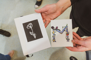 Artystyczne Ferie - tydzień II - Na fotografii uwieczniono grupę uczestników – dzieci, młodzież oraz dorosłych – zaangażowanych w warsztaty tworzenia Artbooków. Widoczne są różnorodne narzędzia, w tym prasa drukarska, z których korzystają pod czujnym okiem prowadzących.