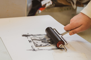 Artystyczne Ferie - tydzień II - Na fotografii uwieczniono grupę uczestników – dzieci, młodzież oraz dorosłych – zaangażowanych w warsztaty tworzenia Artbooków. Widoczne są różnorodne narzędzia, w tym prasa drukarska, z których korzystają pod czujnym okiem prowadzących.