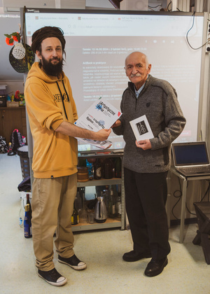 Artystyczne Ferie - tydzień II - Na fotografii uwieczniono grupę uczestników – dzieci, młodzież oraz dorosłych – zaangażowanych w warsztaty tworzenia Artbooków. Widoczne są różnorodne narzędzia, w tym prasa drukarska, z których korzystają pod czujnym okiem prowadzących.