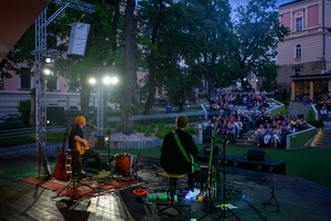 Koncert: Skubas - Duet Akustycznie - Na amfiteatralnej scenie grający na gitarach Marcin Grabiński i Skubas, w tle publiczność