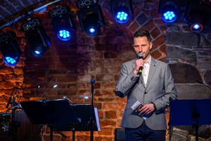 Koncert jazzowy: New Bone - Scena w Piwnicach TCK, na środku przemawia do mikrofonu Sebastian Szafarz - konferansjer,