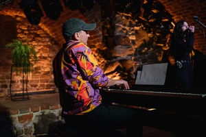 Koncert: Pracownia Piosenki "Na przekór" - Podczas koncertu. Na scenie Grzegorz Gawlik gra na pianinie.