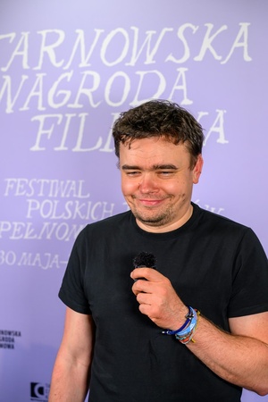 39. TNF: Dzień 6 (4.06.2025) - W hallu kina na ściance 39. TNF pozujący do zdjęcia reżyser Jan P. Matuszyński