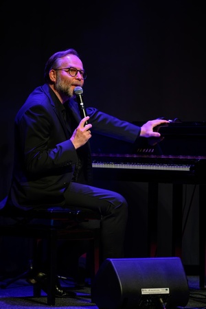 39. TNF: Gala Wręczenia Nagród (7.06.2025) - Na scenie na pierwszym planie pianista Krzysztof Herdzin zapowiadający przed publicznością kolejny utwór