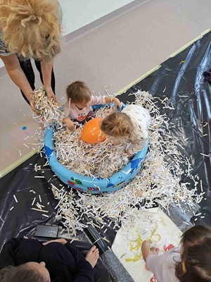 Warsztaty sensoplastyczne - Uczestnicy warsztatów wraz z opiekunem podczas zabawy w baseniku ze ścinkami papieru