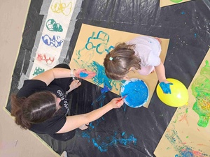 Warsztaty sensoplastyczne - Uczestniczka warsztatów wraz z opiekunką malują farbami