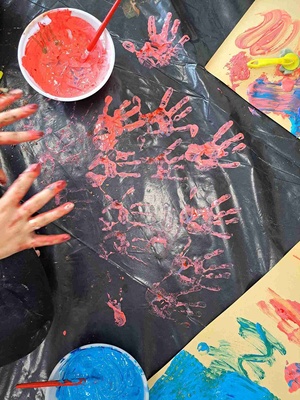 Warsztaty sensoplastyczne - Dłonie oraz odbicie dłoni w kolorze czerwonym na czarnej folii