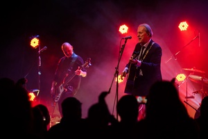 Koncert: John Porter - Helicopters'45 - Na scenie grający na gitarze i śpiewający John Porter, w tle grający na basie Jacek Szafraniec